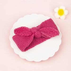 Détail du bandeau tricoté épais pour bébé en rouge rose avec un design de nœud torsadé