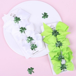 Detailed view of Saint Patrick's Day bow hair clips with glittery green shamrock centers