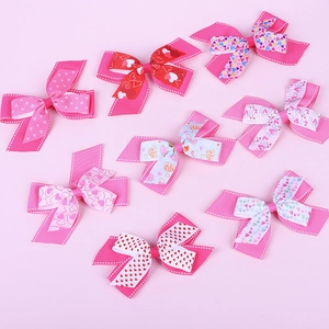 Close-up of pink bow hair clips with love heart patterns and textured grosgrain ribbon