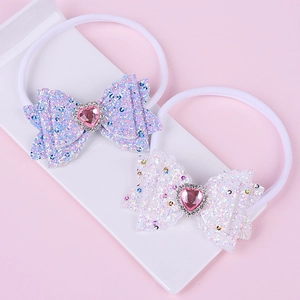Detail of two nylon baby headbands with sequin bows and heart-shaped rhinestones
