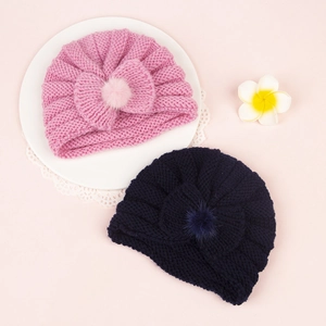 Close-up of knit baby hats with bow and fuzzy pom-pom in pink and navy blue