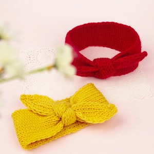 Détail de bandeaux tricotés à oreilles de lapin en rouge et jaune sur dentelle