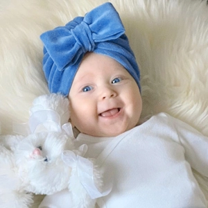 Bonnet turban bébé en velours bleu roi avec grand nœud sur fond en peluche
