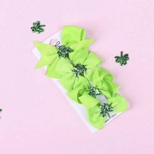 Detail of four green bows with sequin shamrocks for St. Patrick's Day set on card