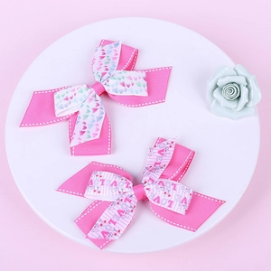 Close-up of pink layered bow hair clips with LOVE heart patterns and polka dot edges
