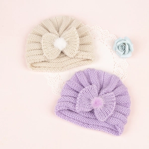 Detailed knit texture of infant turban hats with soft pom poms and large bows