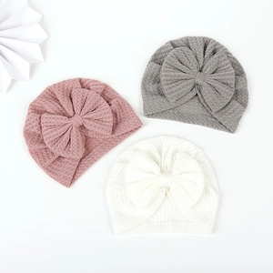 Three-piece baby waffle knit turban hats with large bows in pink, grey, and white
