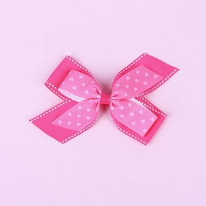 Detail view of pink double layered bow hair clip with white heart patterns and stitching
