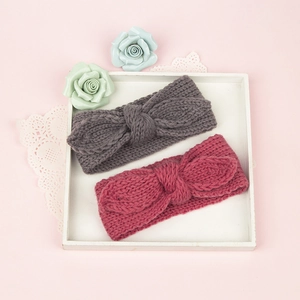 Détail de bandeaux tricotés pour bébé avec nœud papillon en gris et rose foncé