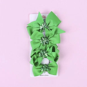 Detail of four green St. Patrick's Day clover bow hair clips on display card