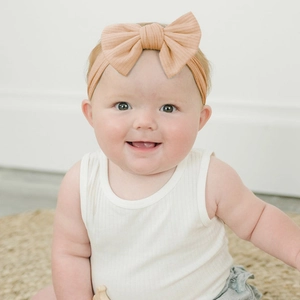 Detail of peach ribbed cotton baby headband with a large decorative bow tie