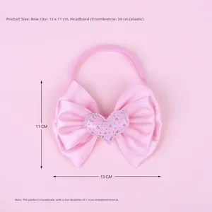 Detail view of pink silk bow headband with a sparkling heart patch and elastic nylon strap