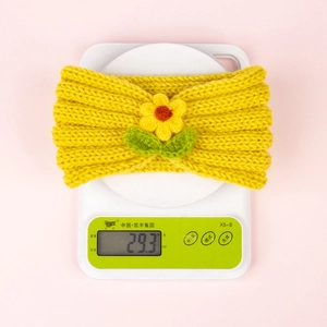 Détail du poids du bandeau en tricot de 29,3g avec fleur jaune et feuilles vertes