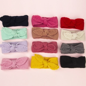 Vue à plat de 12 bandeaux en tricot de couleurs assorties pour bébés sur fond rose