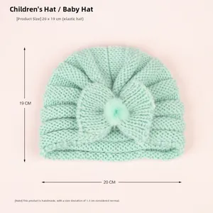 Detail of mint green knit baby hat with bow and pompom, showing 20x19cm size and stretch