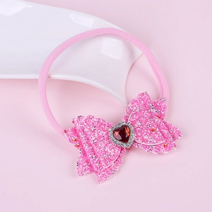 Detail of pink nylon headband with sequin bow and heart-shaped rhinestone centerpiece