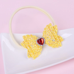 Detail of yellow sequin bow headband with a red heart gem for babies and toddlers