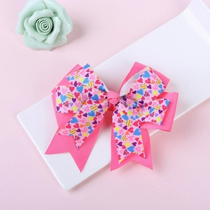 Détail d'un nœud à cheveux rose multicouche avec imprimé cœurs colorés et ruban grain