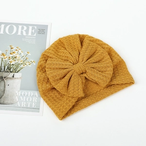Detailed view of ginger yellow waffle knit baby turban hat with a large bow decoration