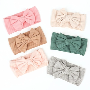 Detailed view of six ribbed cotton baby headbands with large bows in various soft colors