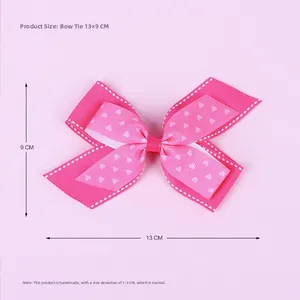 Detail shot of a handmade pink bow hair clip with white heart prints measuring 13 x 9 cm