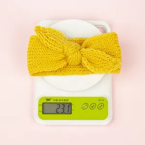 Détail du bandeau en maille jaune gingembre avec nœud posé sur une balance