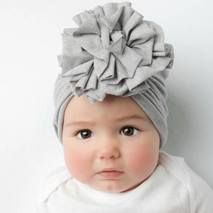 Dettaglio del cappello a turbante per neonati grigio chiaro con grande fiore di stoffa