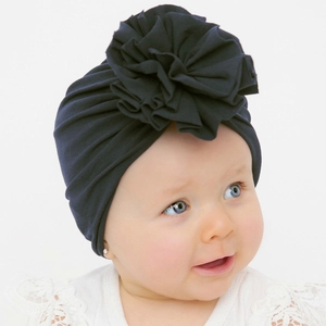 Dettaglio del turbante per neonati blu navy con grande fiore di stoffa su un neonato