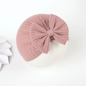 Detailed close-up of a soft waffle knit baby turban hat with a large decorative bow