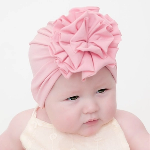 Dettaglio del grande fiore in tessuto e maglia morbida sul cappello a turbante rosa