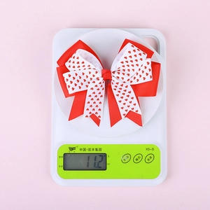 Détail du nœud papillon multicouche rouge et blanc de 11,2g avec motifs de cœurs sur balance