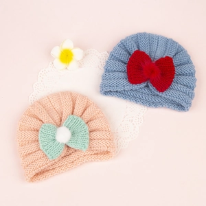Knitted baby turban hats with bows and pom-poms in blue and pink for infant warmth