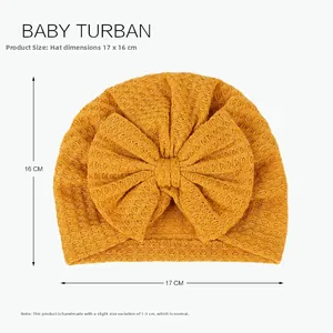 Detailed view of yellow waffle knit baby turban with bow, sizing 17x16 cm