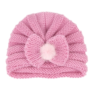 Pink infant knitted turban hat with a large bow and fluffy faux fur pompom detail