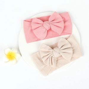 Close-up of pink and beige ribbed knit headbands with large handmade decorative bows