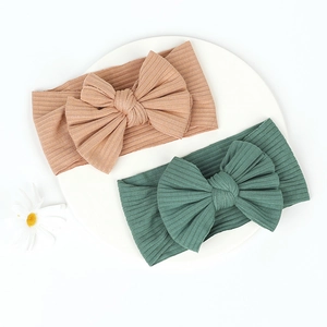 Close-up of cotton ribbed baby headbands with large bows in lotus pink and dark green