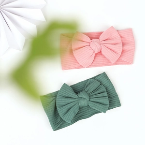 Flat lay of pink and dark green ribbed cotton baby headbands with large bows