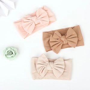 Flat lay of cotton ribbed baby headbands with large bows in pink, beige and coffee colors