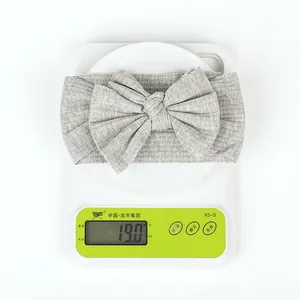 Detailed top view of a dark grey ribbed bow headband weighing 19 grams on a white scale