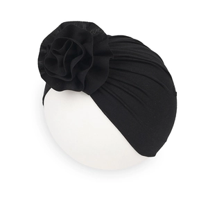 Dettaglio del turbante nero per neonati con una grande decorazione floreale in rilievo