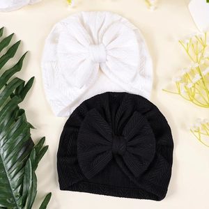 Détail de bonnets turbans pour bébé en noir et blanc avec grands nœuds et tissu texturé