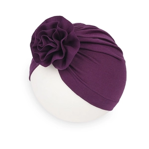 Dettaglio di un cappello a turbante viola per neonati con un grande fiore decorativo 3D
