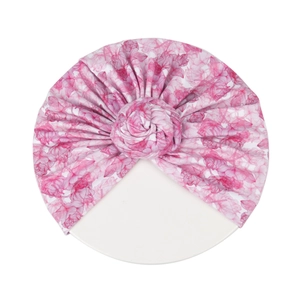 Gros plan d'un bonnet turban rose à fleurs pour bébé avec noeud torsadé et tissu doux