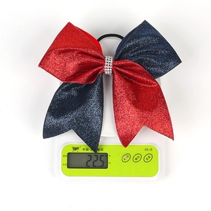Detail of red and blue glitter bow hair tie with rhinestones on a scale showing 22.5g weight