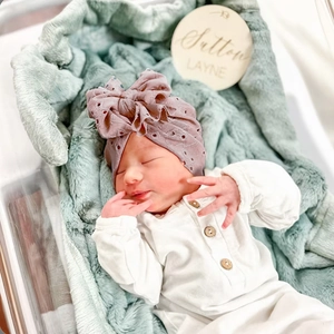 Détail du bonnet turban pour bébé en broderie anglaise avec grand nœud mauve