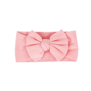 Pink ribbed cotton baby headband with a large handmade knot bow for infants