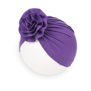 Dettaglio di un cappello a turbante viola scuro con un grande fiore a pieghe in tessuto