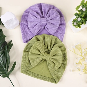 Détail de turbans pour bébés en violet et vert avec une texture douce en maille tissée