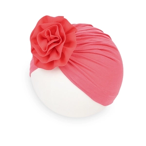 Dettaglio del turbante rosa corallo per neonati con grande fiore decorativo e pieghe