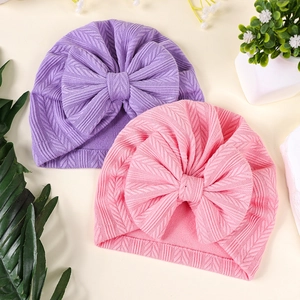 Détails de bonnets turban bébé montrant la maille chevrons et les grands nœuds